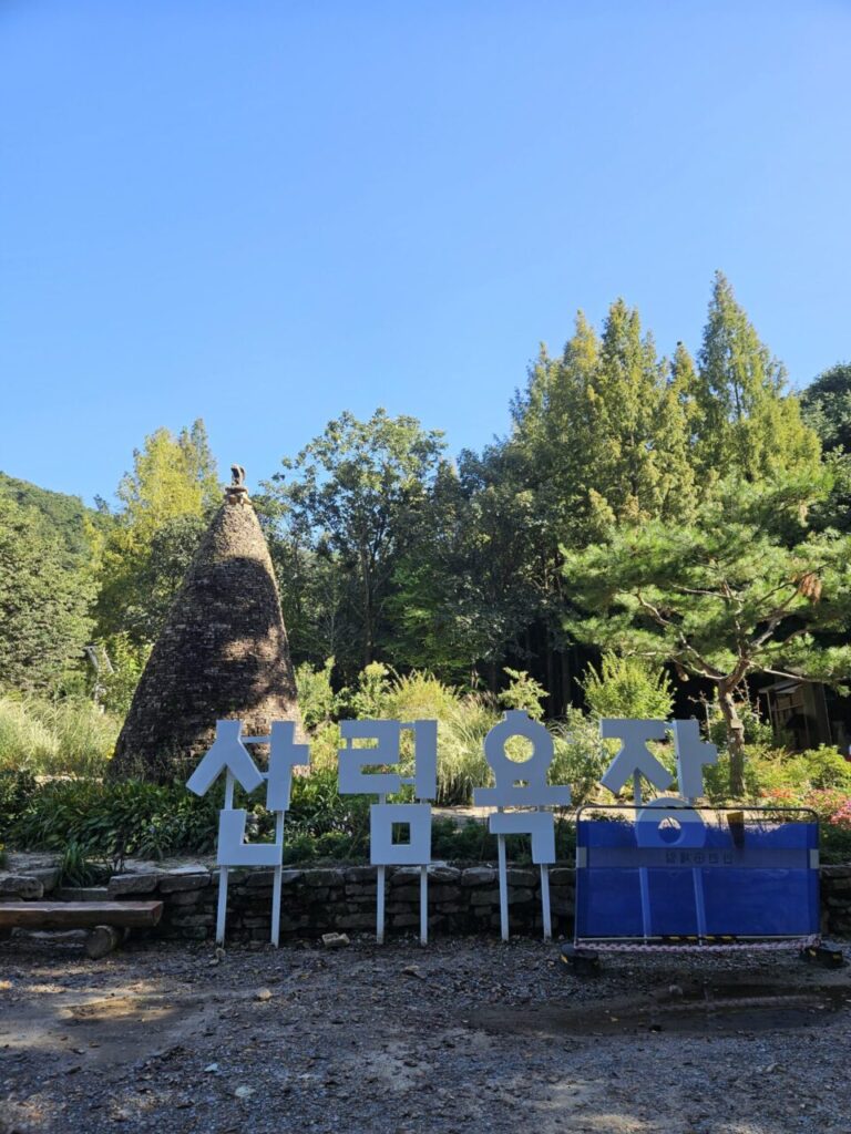 대전 상소동 산림욕장 입구에 세워진 '산림욕장' 글자 조형물과 푸른 하늘, 울창한 숲 풍경