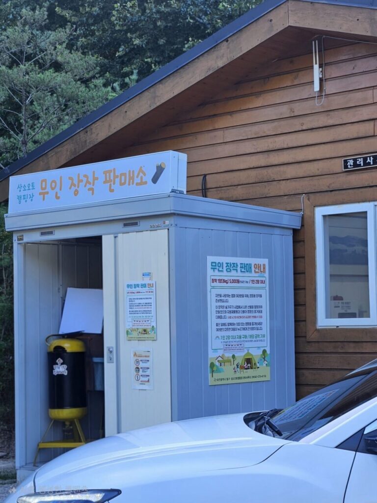 상소동 산림욕장 내 상소오토 캠핑장의 무인 장작 판매소 전경. 캠핑 필수품인 장작을 판매하는 무인 시설과 구매 안내문이 보인다.
