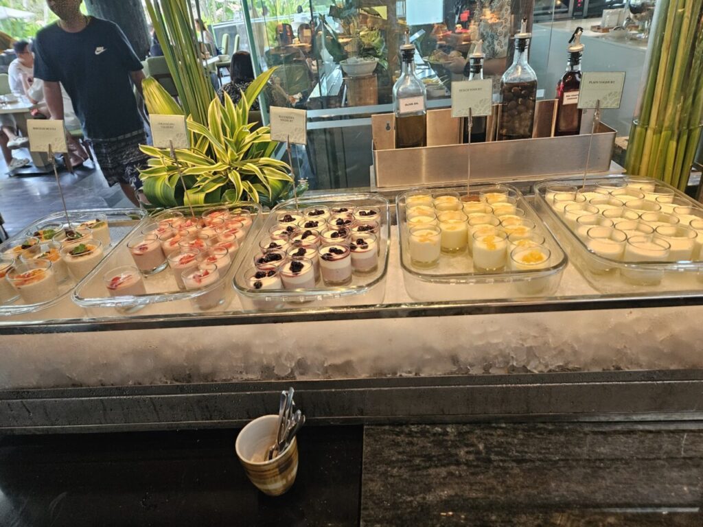 아야나 에스테이트 조식 뷔페의 차가운 디저트 코너입니다. 요거트나 판나코타 같은 작은 컵 디저트들이 다양한 과일 토핑과 함께 얼음 위에 진열되어 있습니다.