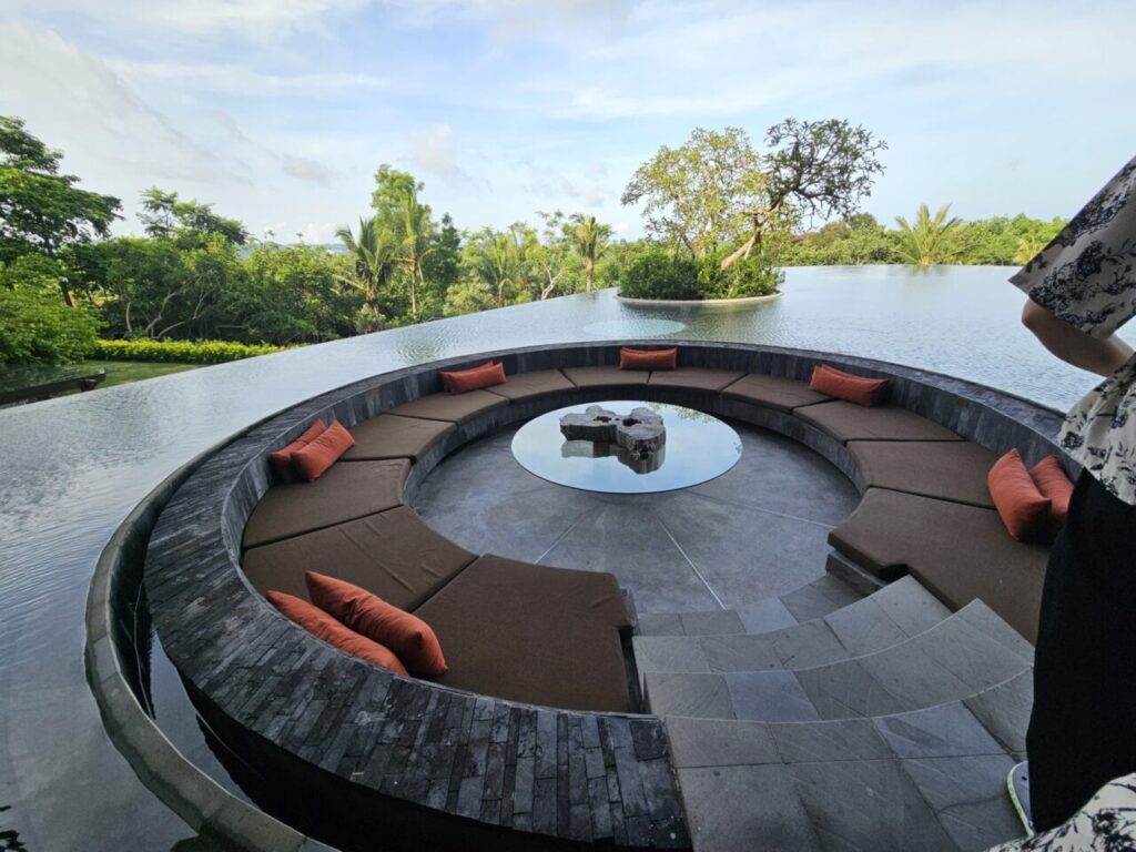 푸른 풍경을 배경으로 한 아야나 리조트의 인피니티 풀 옆에 위치한 독특한 원형 선큰 좌석 공간입니다. 주변의 물과 조화롭게 어우러져 아름다운 전경을 선사합니다.