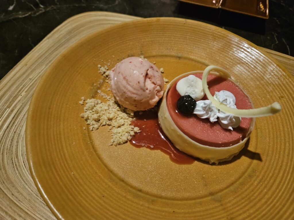 갈색 접시에 담긴 분홍색 무스 케이크와 딸기 아이스크림, 달콤한 크럼블이 어우러진 맛있는 디저트.