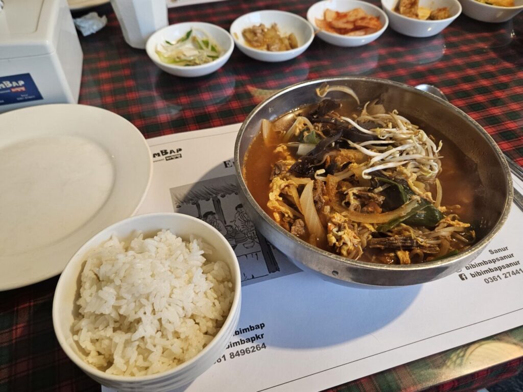발리 한식당 테이블에 차려진 얼큰한 육개장, 따뜻한 흰 쌀밥, 그리고 김치를 포함한 한국식 반찬 여러 가지