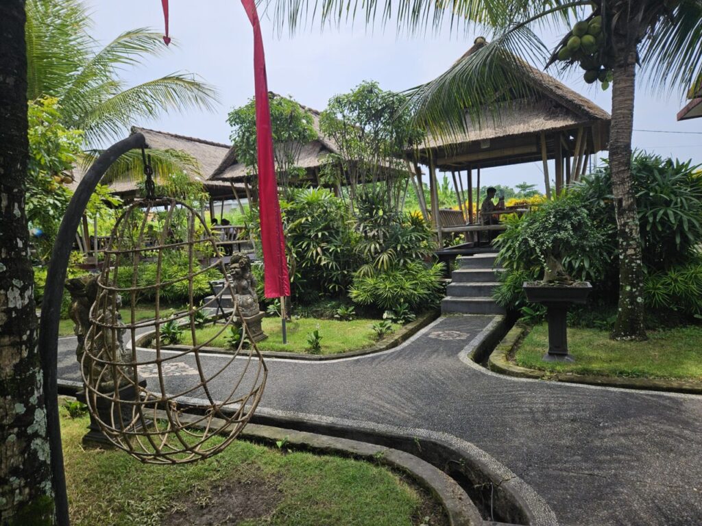 건축물 내부에는 테이블과 의자가 놓여 있으며, 여러 명의 사람들이 앉아 있습니다. 건물 외부에는 녹음이 우거진 나무와 숲이 보이며, 야외에 테이블과 의자가 놓여 있습니다.