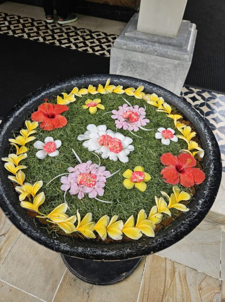 발리 아야나 리조트 로비에 놓인 검은색 물동이에 다양한 색깔의 꽃잎과 꽃으로 아름답게 장식된 모습.