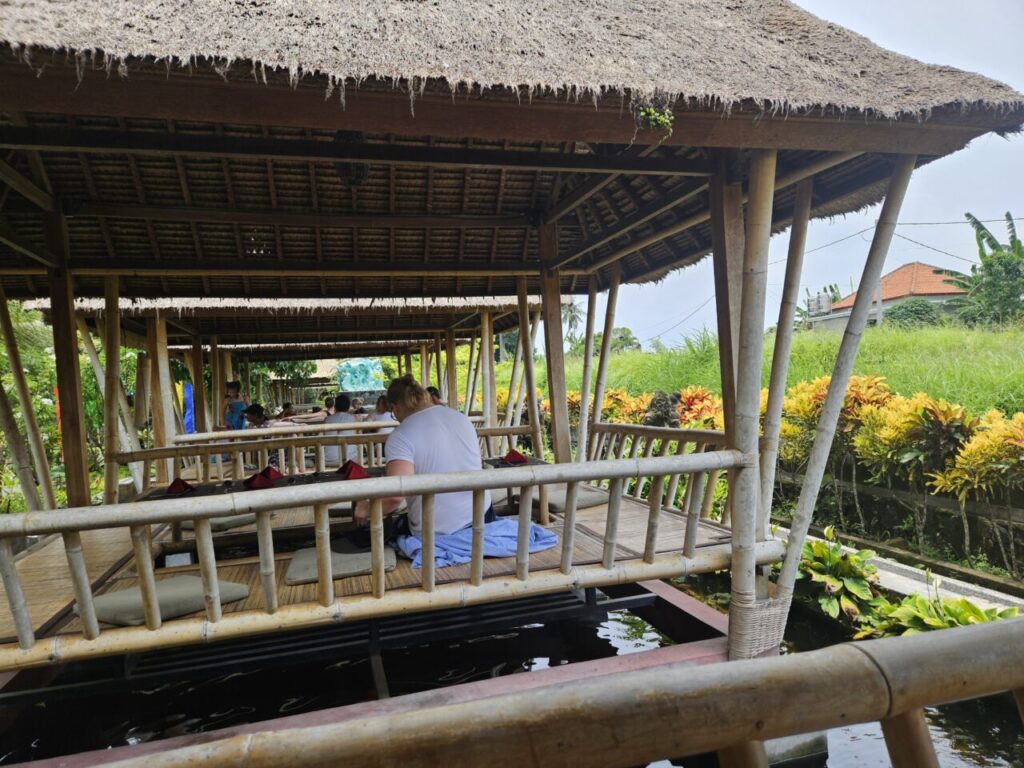 발리 우붓의 야외 식당에서 사람들이 죽 늘어선 테이블에 앉아 식사하고 있는 모습