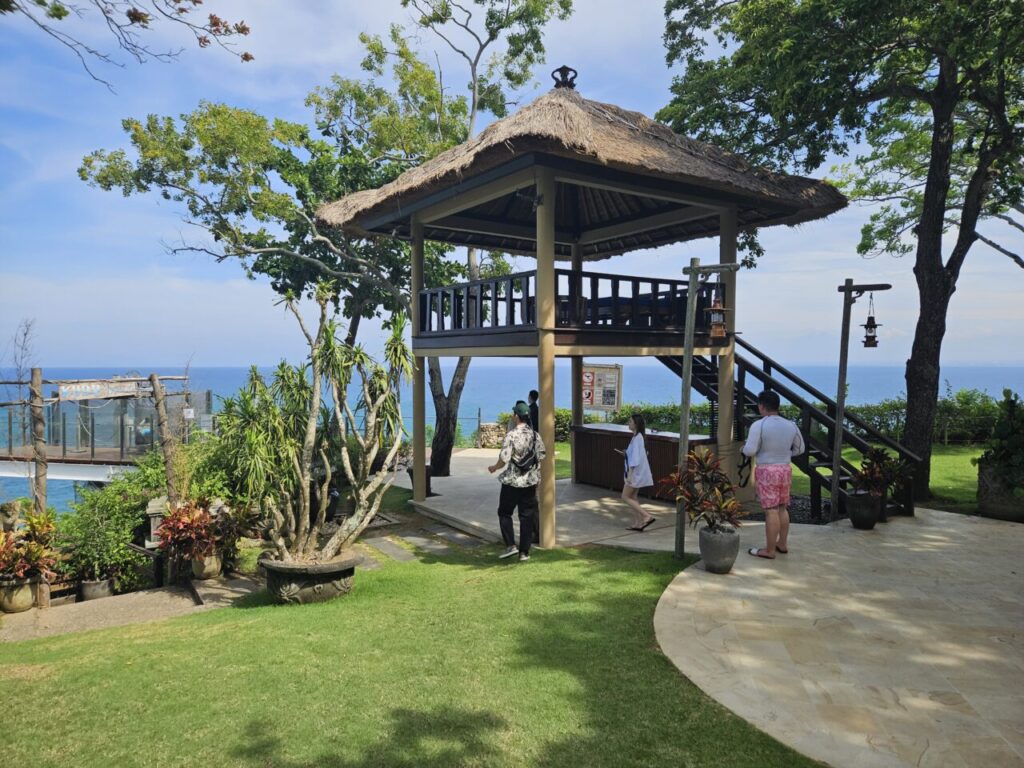 발리 쿠부 비치에 위치한 짚 지붕의 전망대. 탁 트인 바다 전망을 감상할 수 있으며, 사람들이 주변을 오가고 있다.