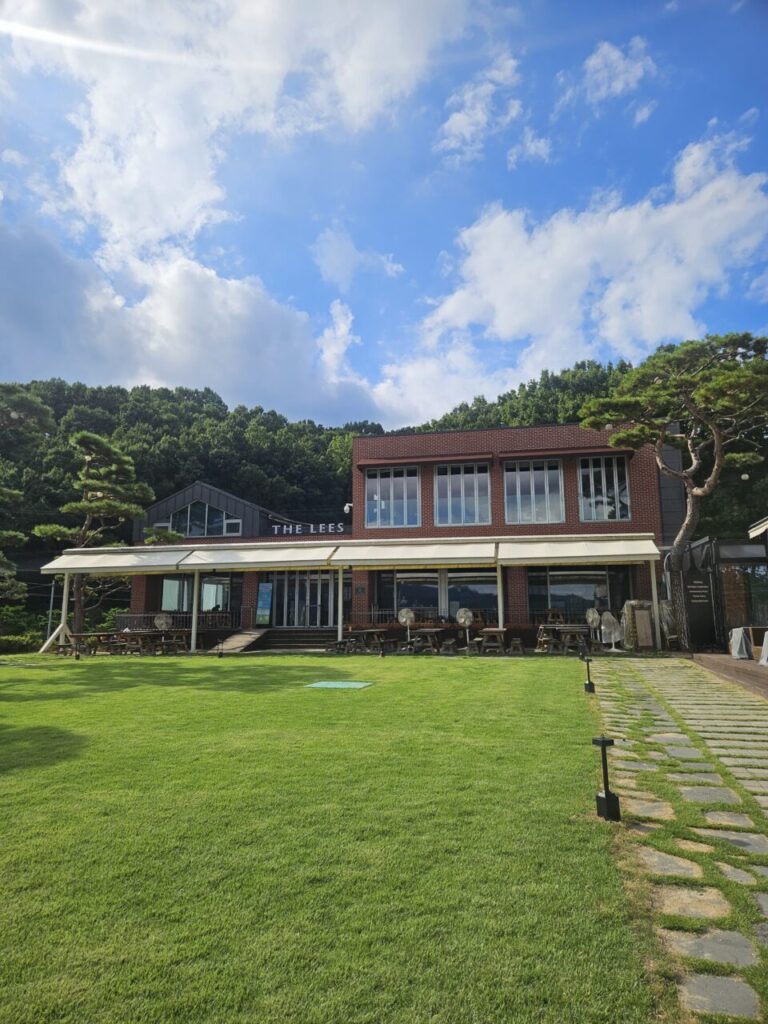 넓은 잔디밭과 돌길이 이어지는 대청호 르 카페(LE CAFE) 건물 외관.