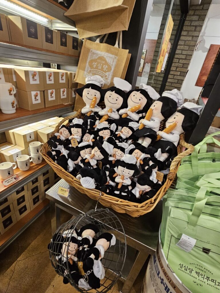 대전 성심당 기념품 코너에 있는 제빵사 캐릭터 인형들. 바게트를 들고 있는 귀여운 인형들이 바구니에 가득 담겨 있다.