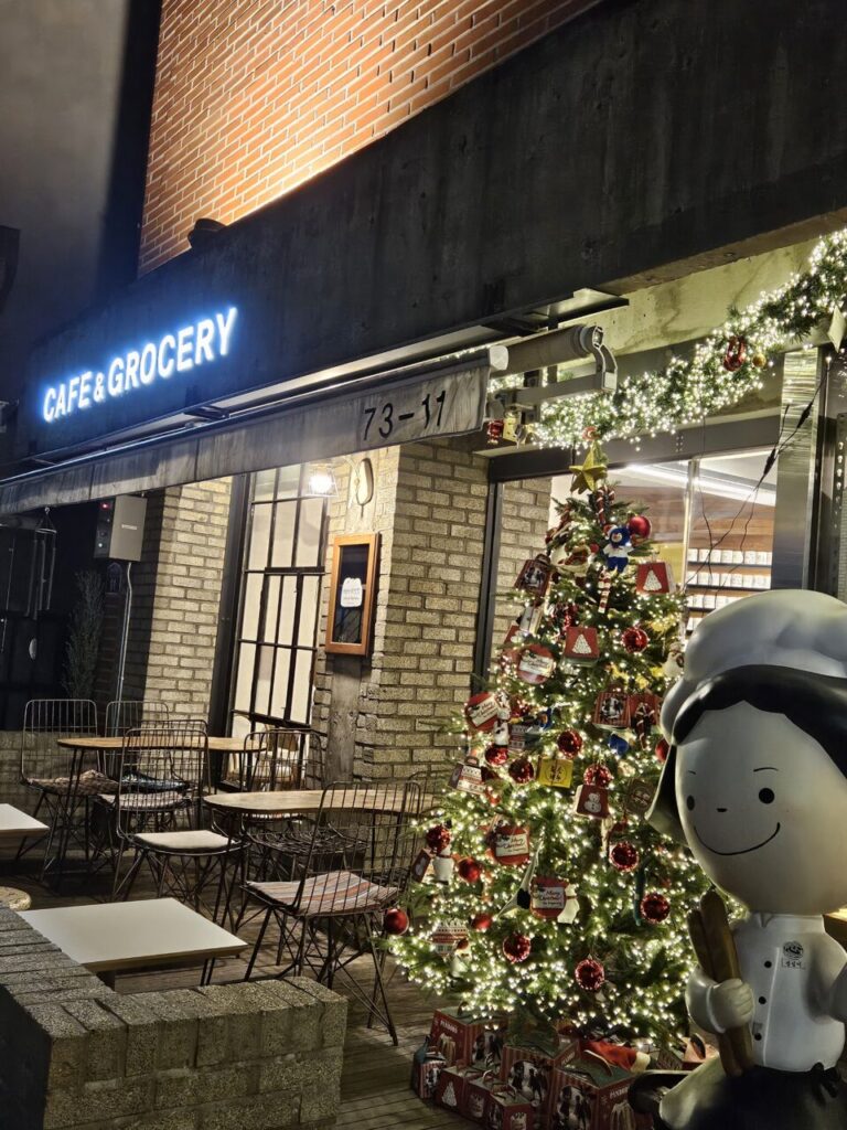 대전 성심당 스트리트의 '카페 & 그로서리' 매장 외관. 크리스마스 장식과 반짝이는 트리가 놓여 있고, 제빵사 캐릭터 조형물이 서 있다.
