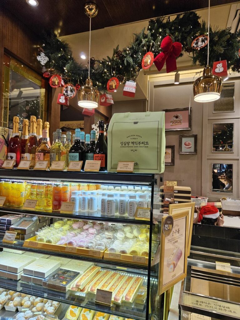 대전 성심당 케이크 부티크 내부 전경. 크리스마스 장식이 화려하게 꾸며져 있고, 다양한 케이크와 빵, 음료들이 진열되어 있다.