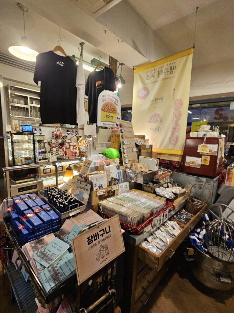 대전 성심당 기념품 매장 내부. 티셔츠, 문구류, 소품 등 다양한 기념품들이 복잡하게 진열되어 있다.