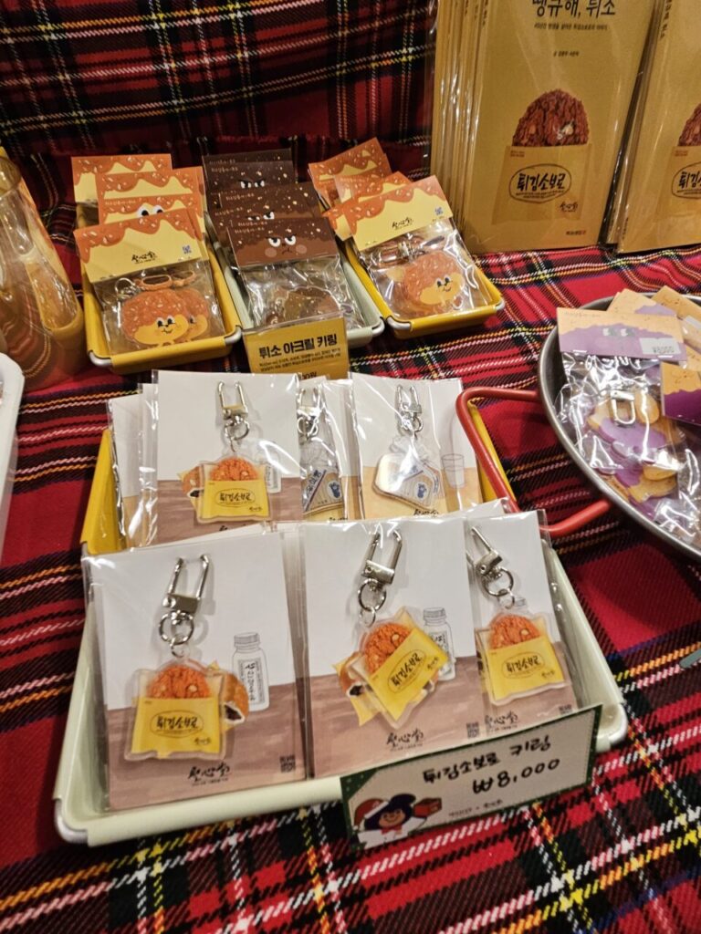 대전 성심당 기념품 매장의 튀소구마 캐릭터 키링 및 소품 진열대. 빨간 체크무늬 테이블 위에 놓여 있다.