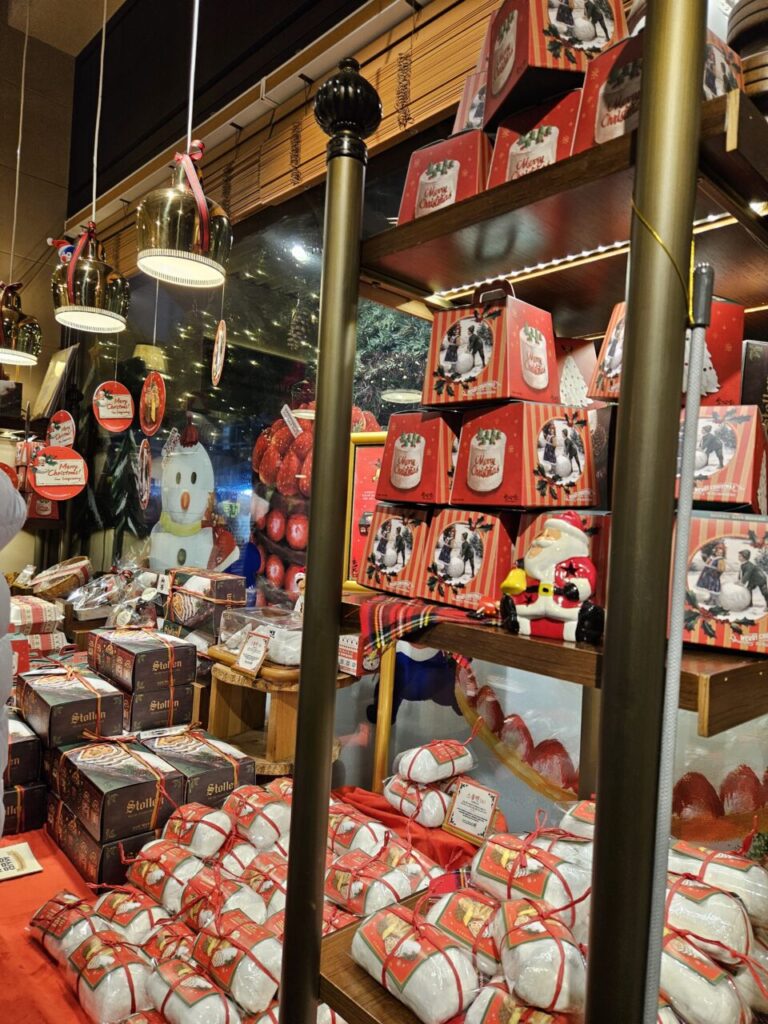 성심당 베이커리의 크리스마스 장식된 쇼윈도우입니다. 눈사람 인형, 크리스마스 장식품들, 그리고 슈톨렌을 비롯한 다양한 선물 상자들이 진열되어 있습니다.