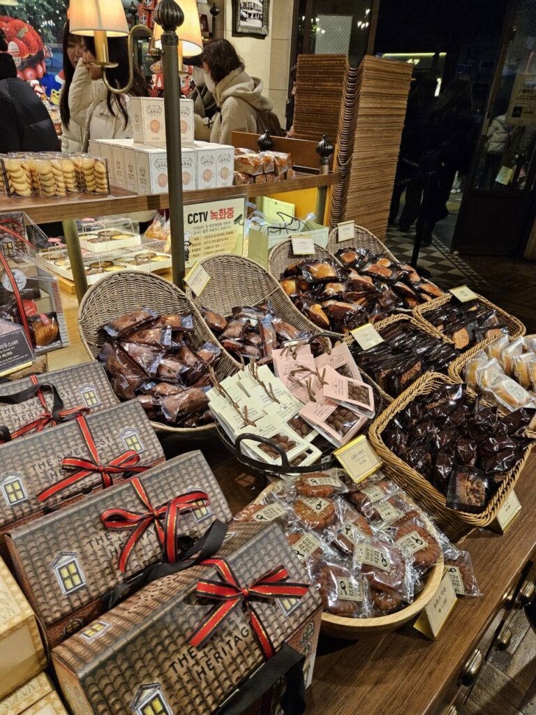 성심당 베이커리에서 다양한 종류의 개별 포장된 빵들과 예쁘게 포장된 선물 상자들이 진열되어 있는 모습입니다. 크리스마스 분위기를 더하는 리본 장식이 눈에 뜁니다.