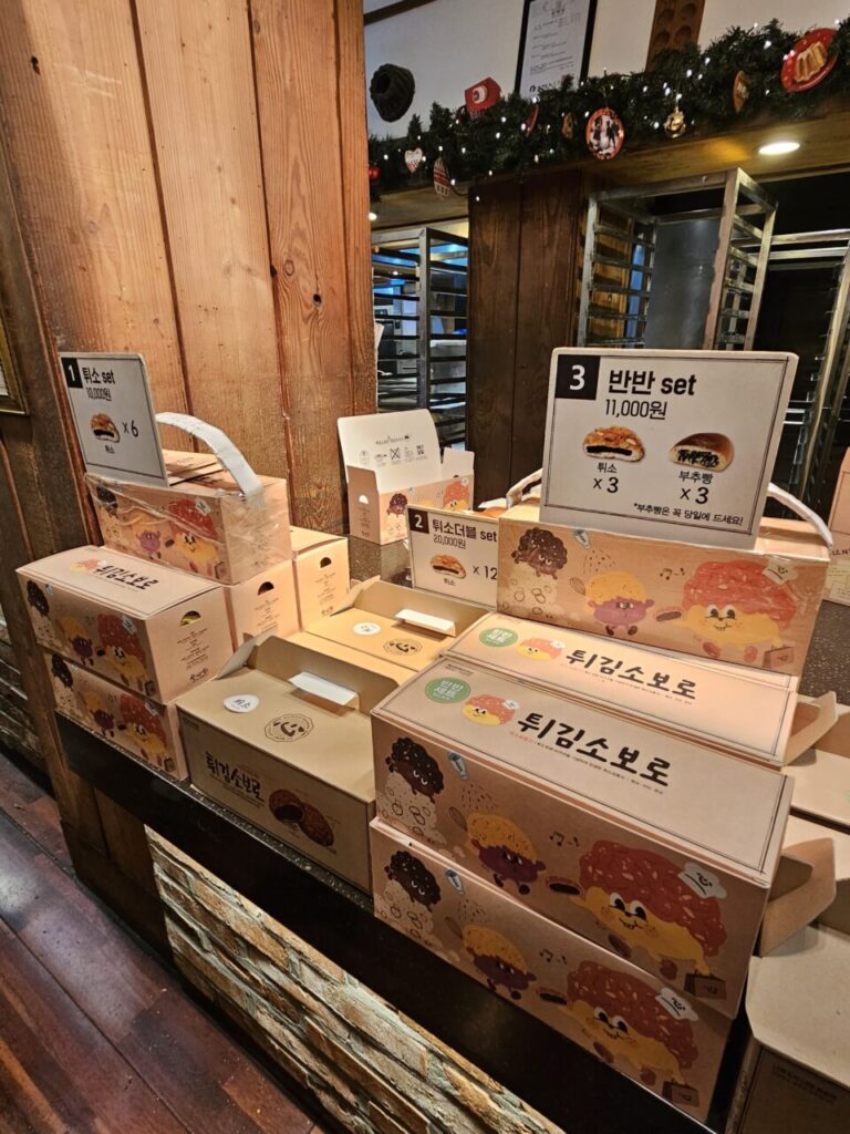 성심당의 대표 메뉴인 '튀소구마'와 '튀소더블' 등 튀김소보로 선물 세트들이 진열되어 있습니다. 다양한 구성과 개수로 포장된 상자들이 보입니다.